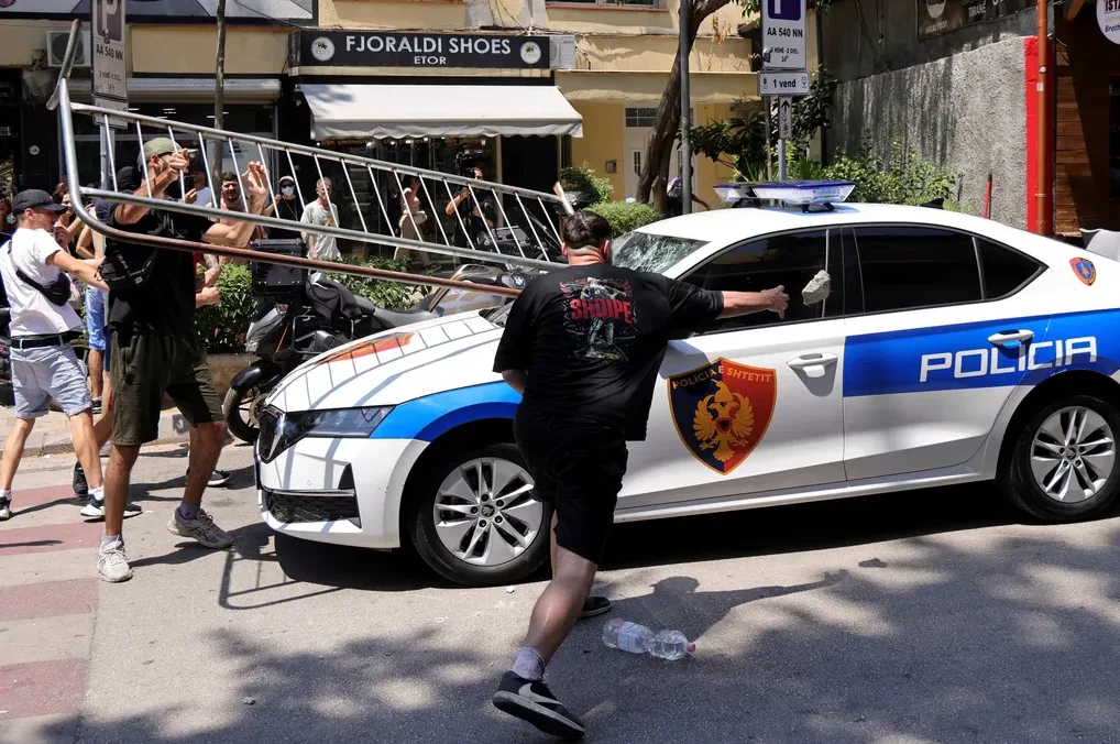 Muškarac baca kamen na policijsko vozilo u proljeće.
