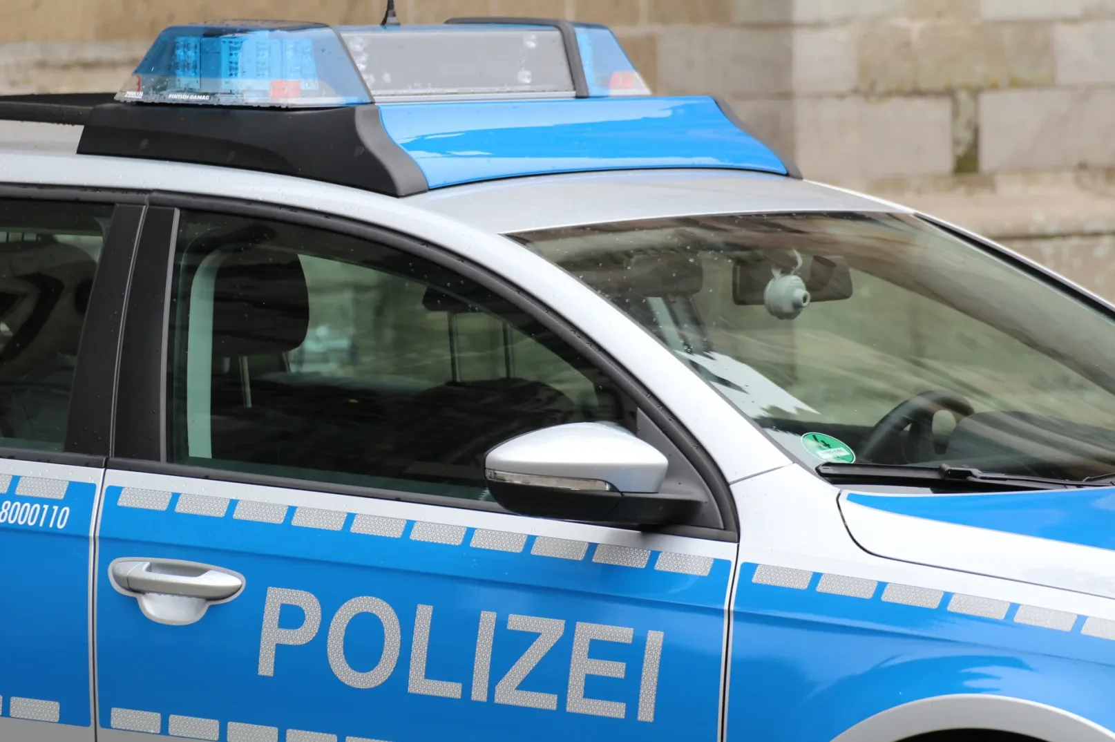 Dio policijskog vozila sa natpisom "POLIZEI" i plavim rotacionim svjetlima.