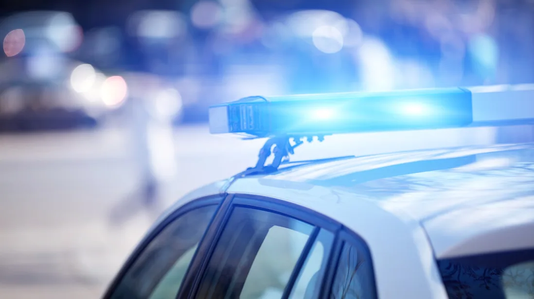 Detalj policijskog vozila sa upaljenim plavim rotacijskim svjetlima.