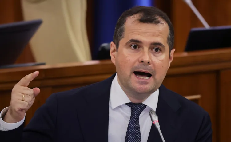 Političar u tamnom odijelu govori sa podignutim prstom.