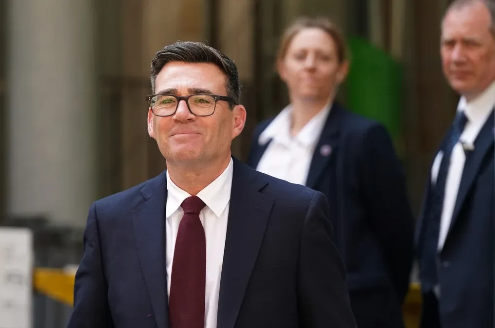 Andy Burnham, britanski političar i gradonačelnik Greater Manchester-a, nosi tamno odijelo, bijelu košulju i bordo kravatu, uz naočare.