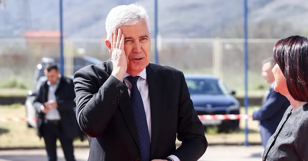 Političar sa rukom na čelu, gleda u stranu.