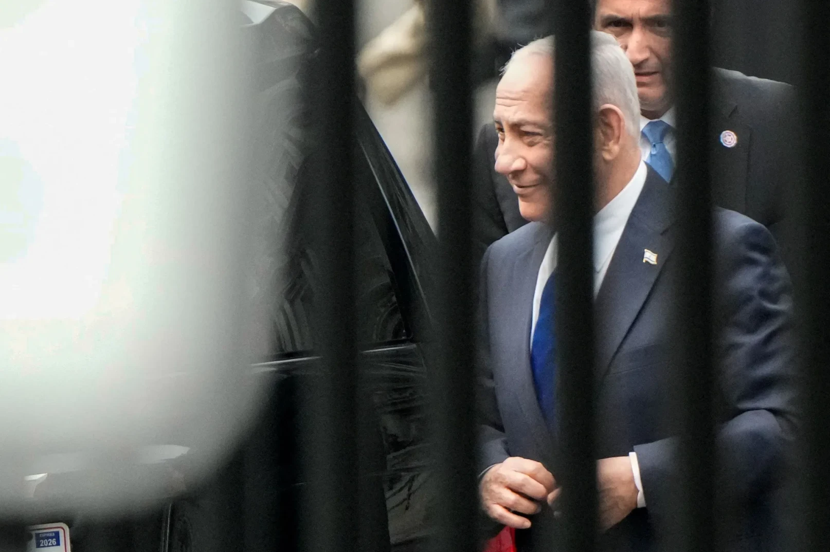 Benjamin Netanjahu u tamnom odijelu i plavoj kravati, sa izraelskom zastavicom na reveru.