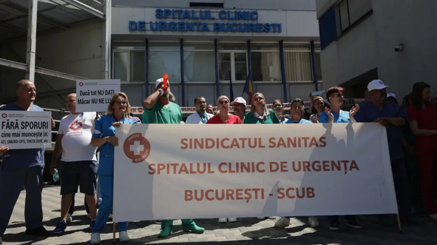 Grupa zdravstvenih radnika drži transparent ispred bolnice u Bukureštu.