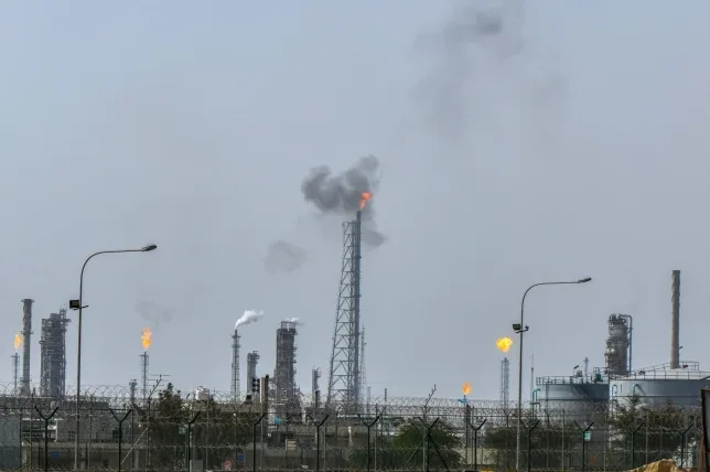 Industrijsko postrojenje sa nekoliko dimnjaka, od kojih neki ispuštaju dim i imaju plamene baklje.