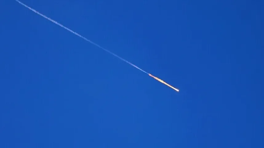 Raketa koja pada kroz plavo nebo sa tragom dima.