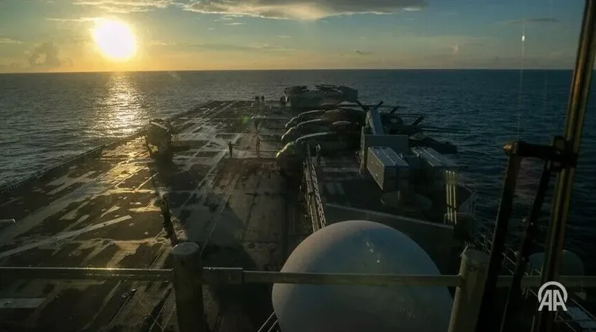 Ratni brod sa helikopterima na palubi tokom zalaska sunca.