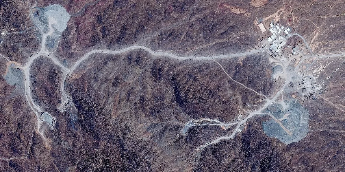 Satellitski snimak rudarskog postrojenja i puteva u brdovitom, suhom predjelu.