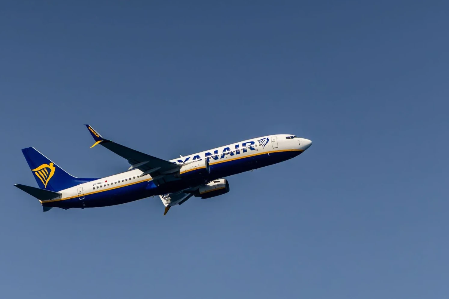 Ryanair avion sa plavim i žutim logom uzlijeće na vedrom nebu.