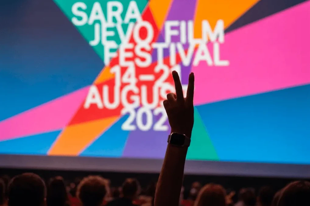 Ruka podignuta sa dva prsta u zraku ispred ekrana Sarajevo Film Festivala