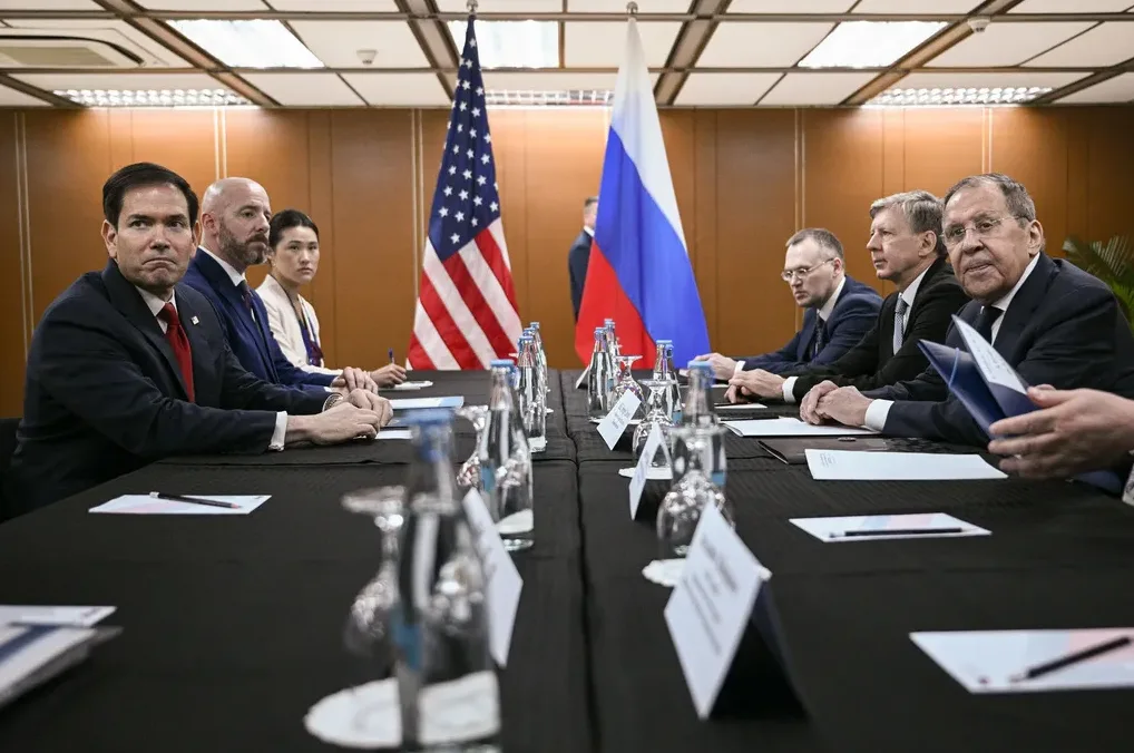 Članovi američke i ruske delegacije sjede za crnim stolom ispred zastava svojih zemalja.