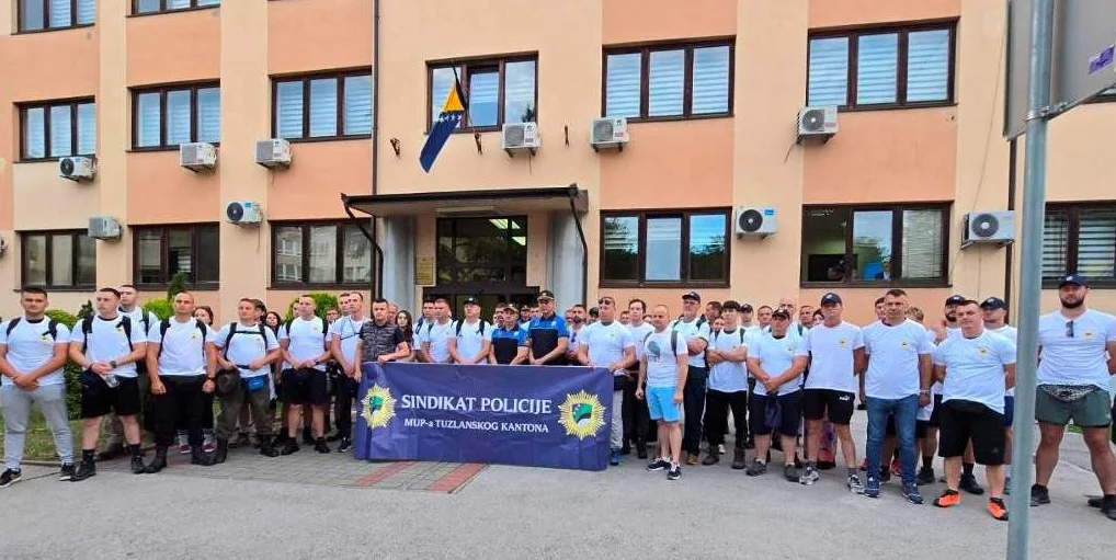 Grupa policajaca u uniformama ispred zgrade MUP-a Tuzlanskog kantona sa natpisom "Sindikat policije MUP-a Tuzlanskog kantona"