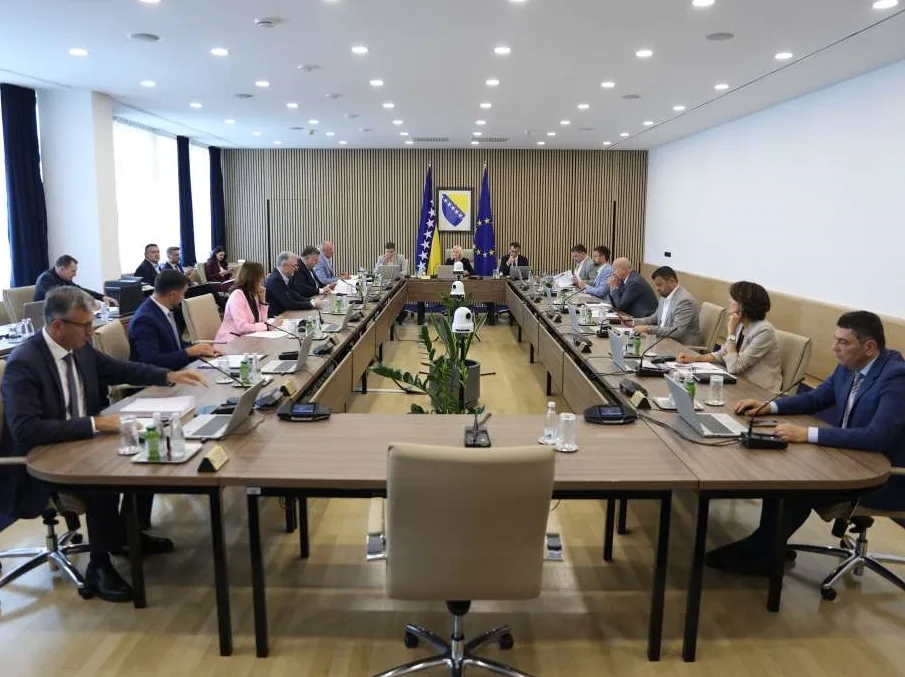 Gledište na sjednici Vlade Federacije Bosne i Hercegovine na kojoj prisustvuje više osoba, sjedeći za velikim U-oblikovanim stolom sa laptopima i dokumentima ispred sebe.