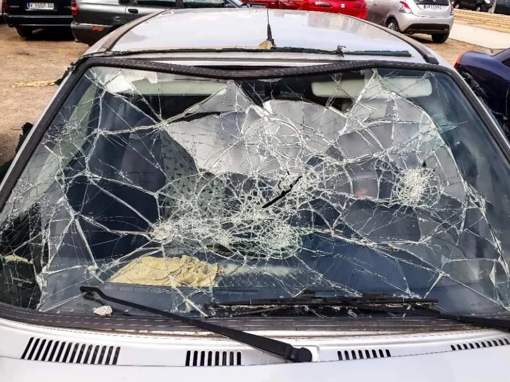 Detaljan pogled na potpuno razbijeno vjetrobransko staklo automobila, sa mnoštvom napuklina koje se protežu preko cijele površine.