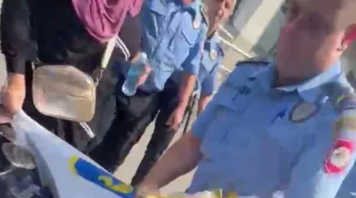 Službenik policije u plavoj uniformi drži zastavu sa plavo-žutim motivima.