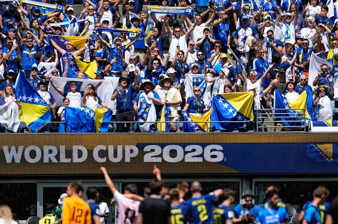 Navijači Bosne i Hercegovine slave na stadionu, držeći zastave Bosne i Hercegovine