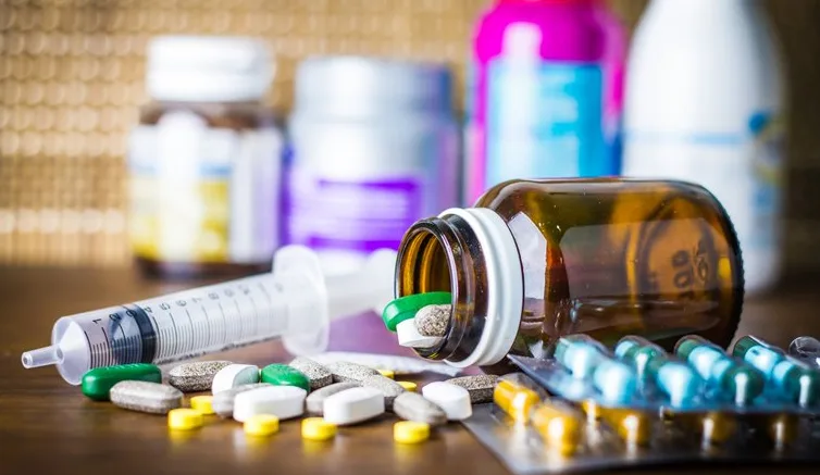 Puno tableta, kapsula i medicinskih sirupa na drvenoj površini.