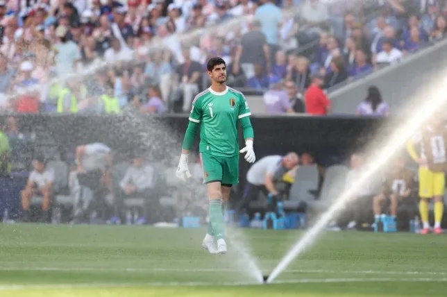 Fudbaler Thibaut Courtois u zelenom golmanskom dresu Belgije stoji na fudbalskom terenu.