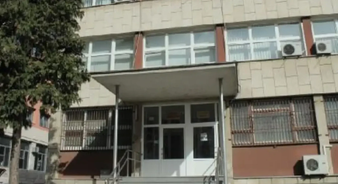 Ulazna vrata i prozori betonsko-staklene zgrade sa metalnim rešetkama.