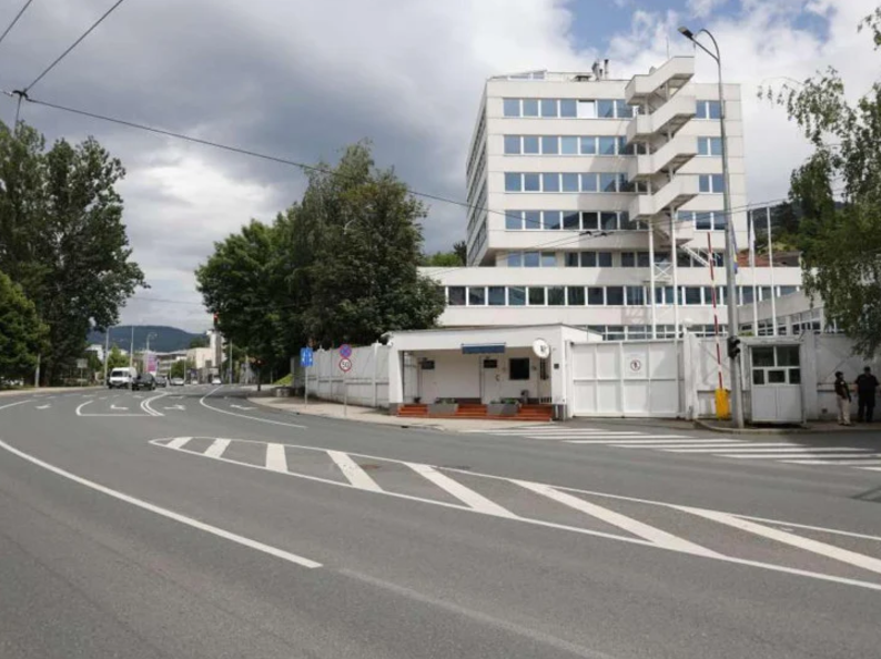 Moderna zgrada u Sarajevu sa velikim bijelim kapijama i osiguranjem