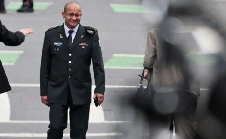 Visoki zvaničnik u tamnoj vojnoj uniformi sa naočarima, koji gleda prema dolje dok hoda.