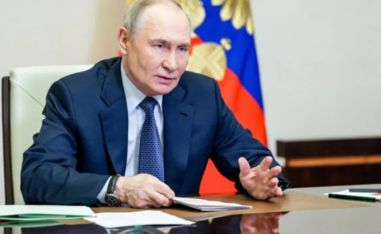 Vladimir Putin sjedi za stolom ispred zastave Rusije