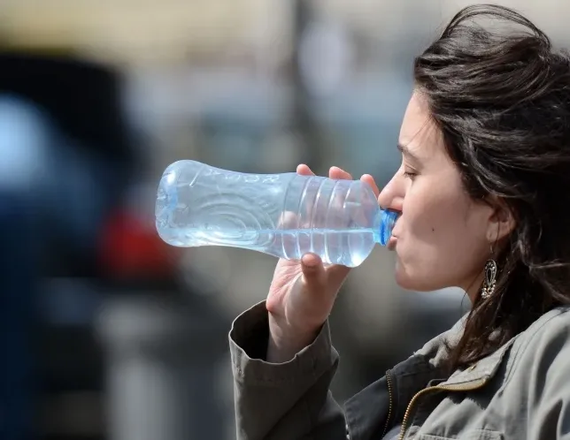 Žena pije vodu iz plastične boce