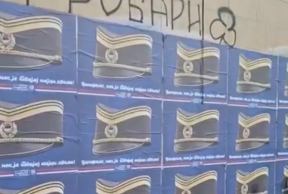 Zidine sa zalijepljenim posterima na kojima se nalaze stilizovane kape sa amblemima i natpisom na bosanskom jeziku