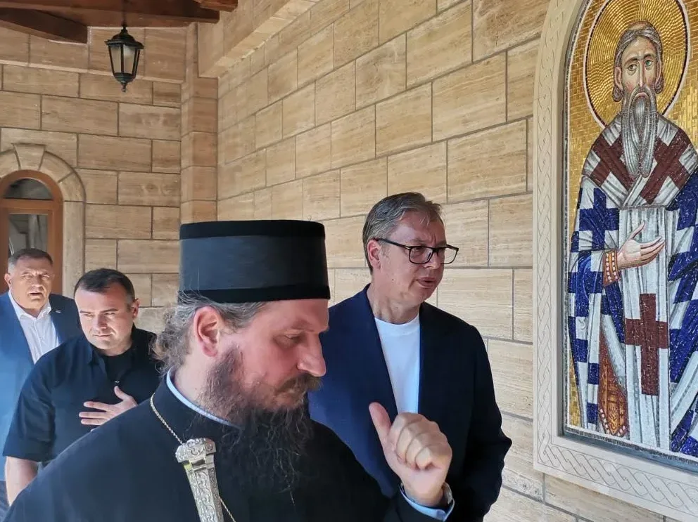 Aleksandar Vučić sa sveštenikom i vjernicima ispred mozaika sveca.