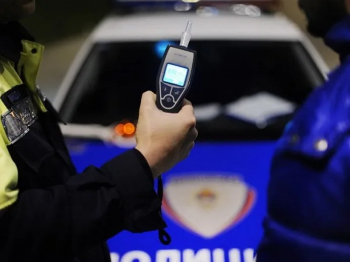 Policajac drži alkotestar ispred policijskog vozila