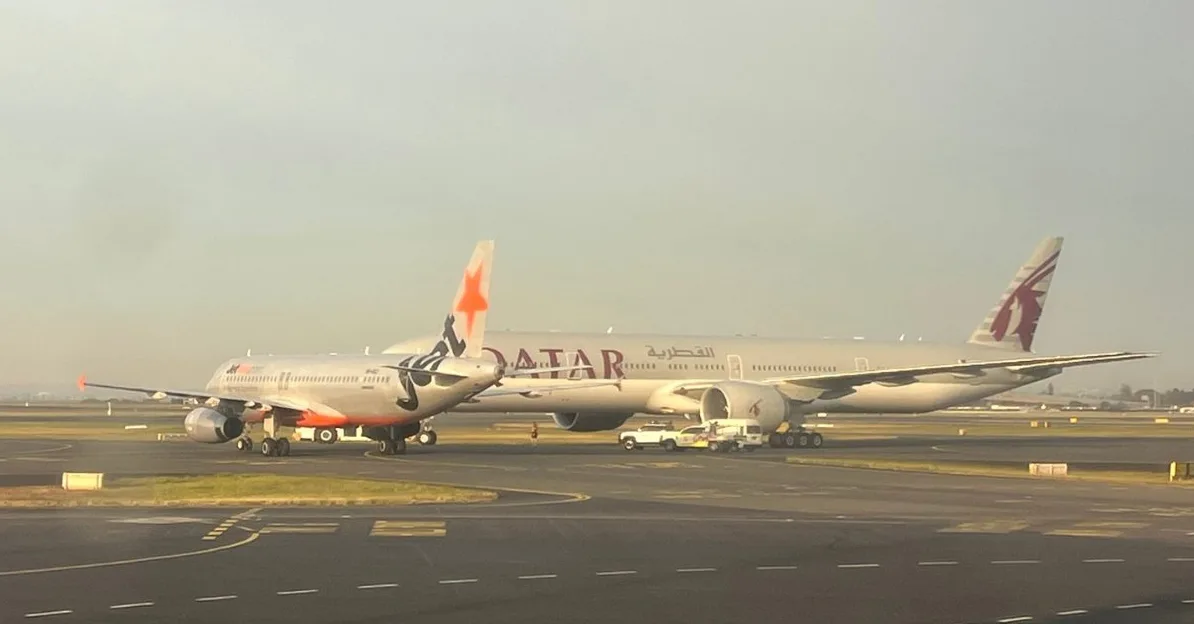 Dva aviona, Qatar Airways i Jetstar, parkirani jedan pored drugog na aerodromskom asfaltu.