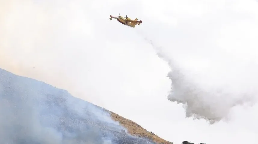 Protivpožarni avion izbacuje vodu na zapaljenu planinsku padinu