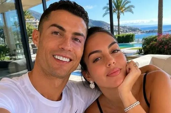 Kristijano Ronaldo i Georgina Rodrigez se smiješe u kameru dok uživaju na ljetovanju sa bazenom i pogledom na more u pozadini.