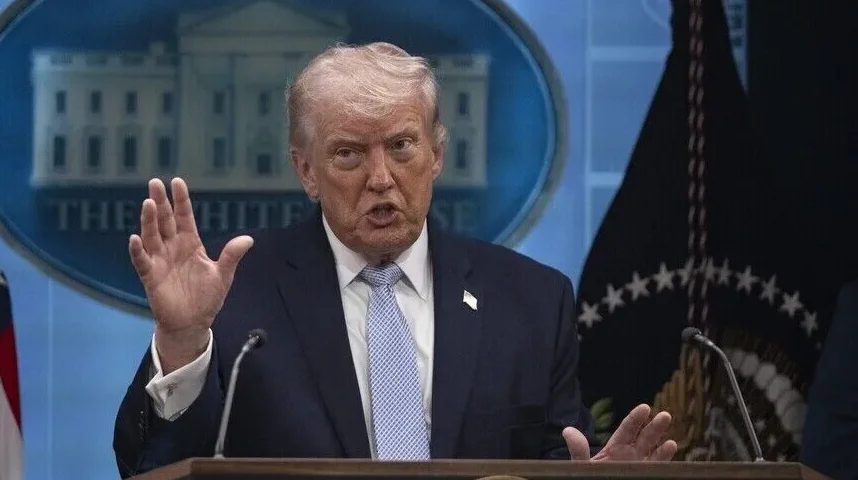 Donald Trump sa podignutom desnom rukom i podignutim kažiprstom, govori iza govornice ispred amblema Bijele kuće.