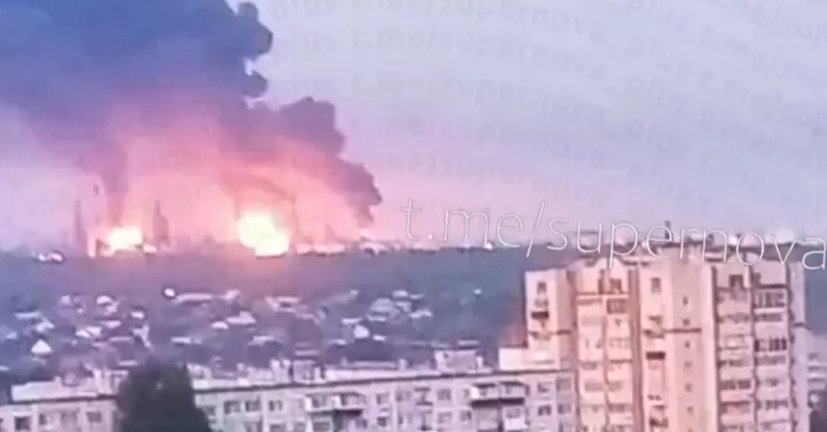 Velika eksplozija sa stubom dima i plamenom iznad urbanog područja, sa zgradama u prvom planu.