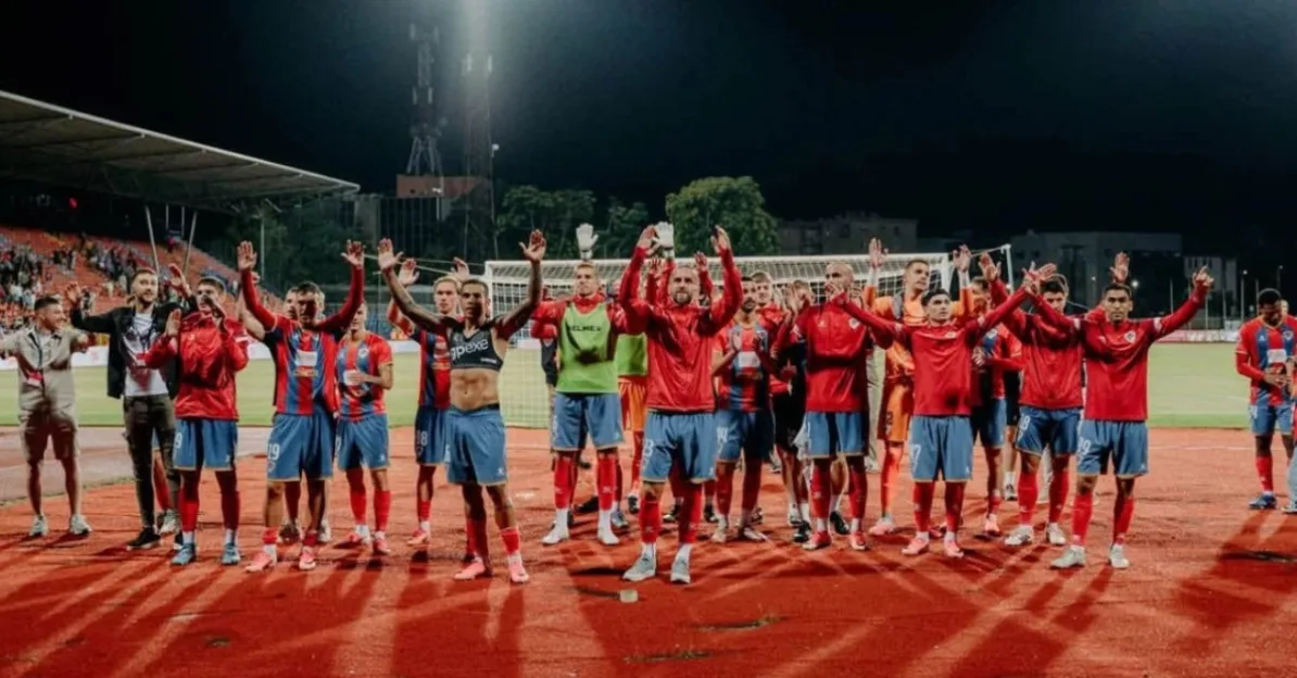 Grupa fudbalera sa podignutim rukama na stadionu
