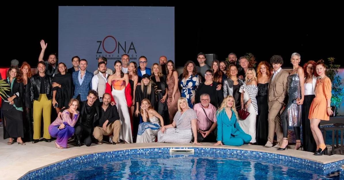 Grupa ljudi pozira ispred bazena sa logom "ZONA TALENT AGENCY".
