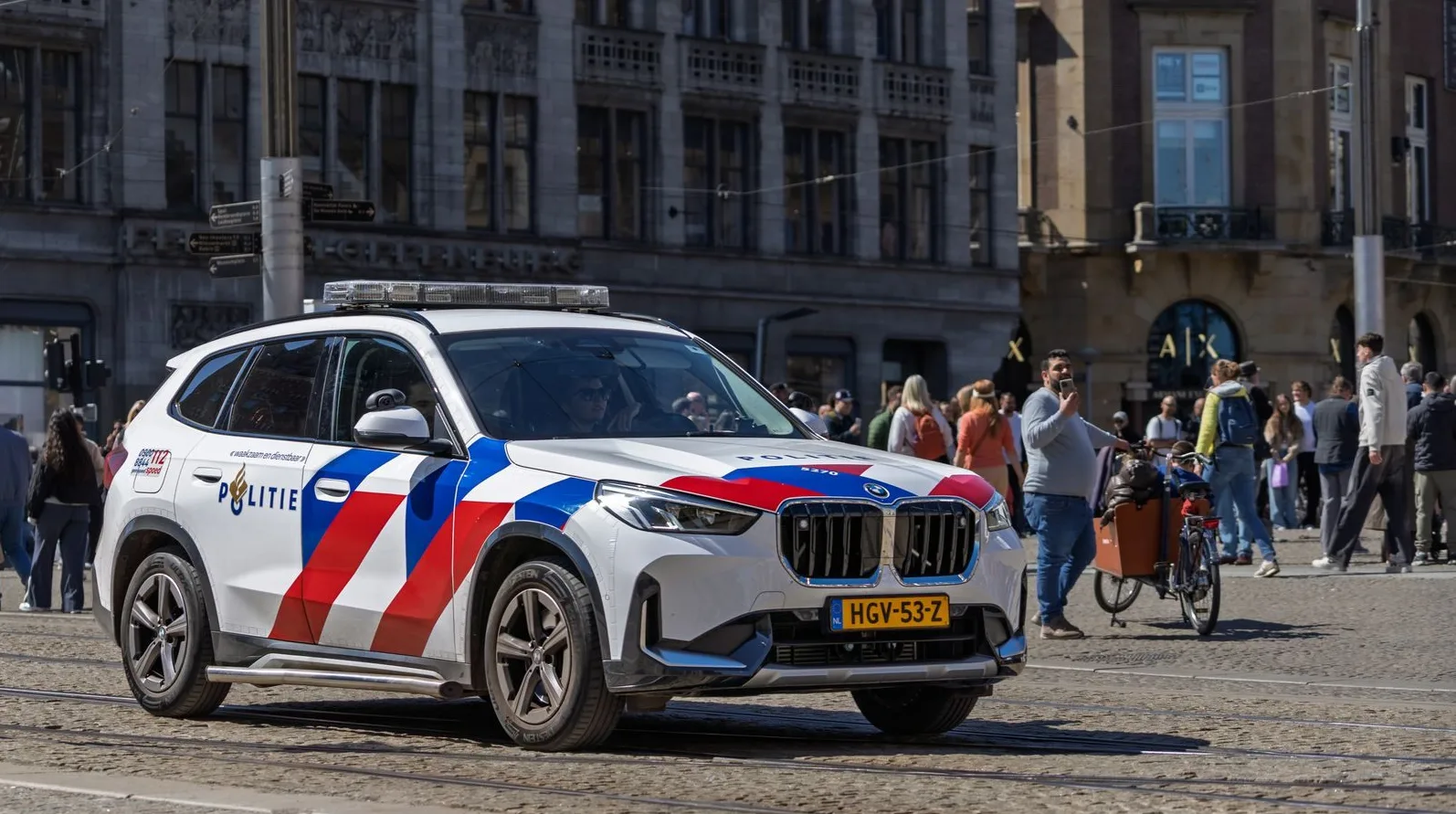 Dutch police SUV patrols in a busy city square, capturing urban life and public safety.