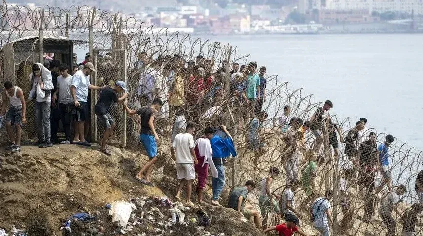 Grupa migranata i izbjeglica penje se preko bodljikave žice i žičane ograde uz brdo prema teritoriji Evropske unije.