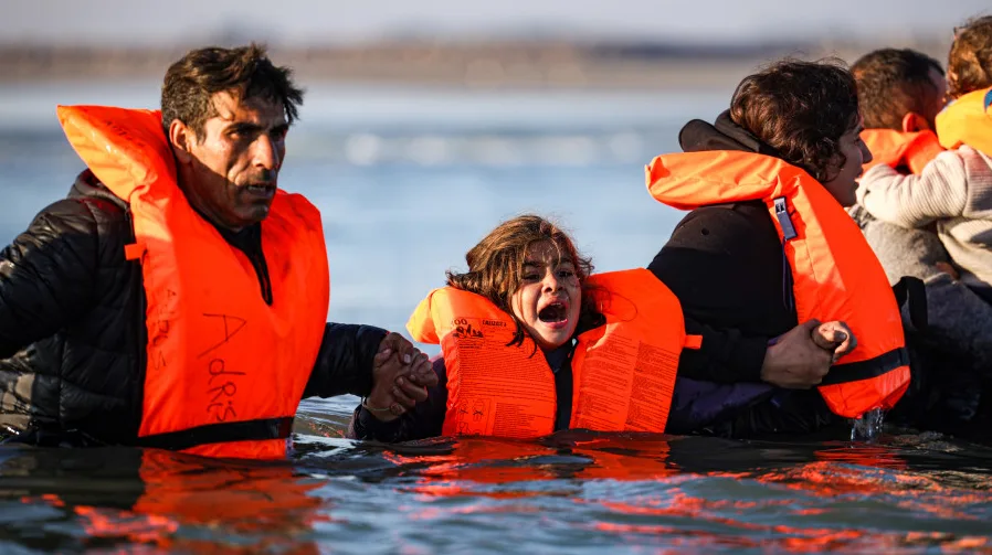 Odrasla osoba i dijete u narandžastim prslucima za spašavanje u vodi