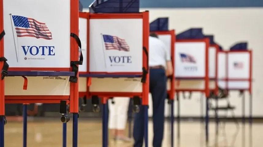 Redovi glasačkih kabina sa američkom zastavom i natpisom "VOTE".