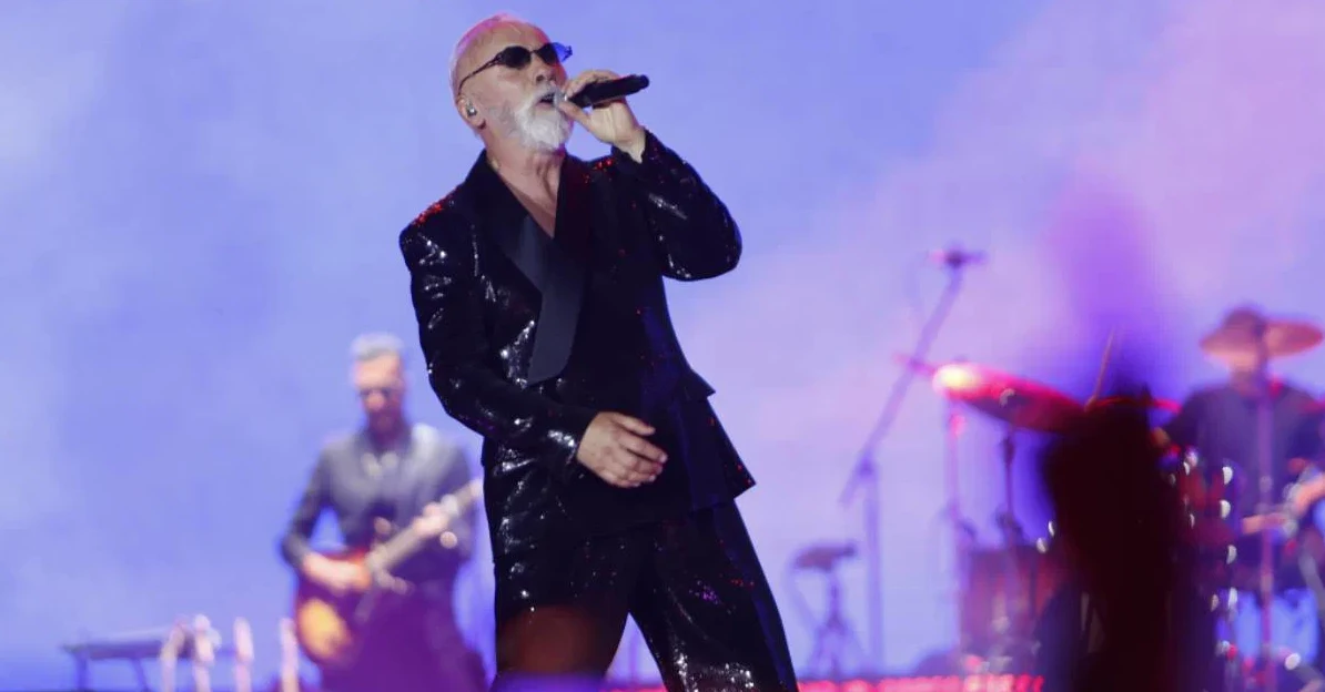 Muzičar u šljokičastom crnom odijelu pjeva na bini