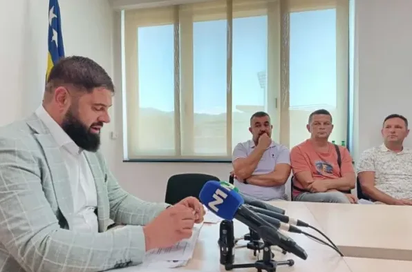 Muškarac sa bradom u odijelu govori za govornicom, pored njega sjede tri muškarca, a ispred njih su mikrofoni N1 televizije.