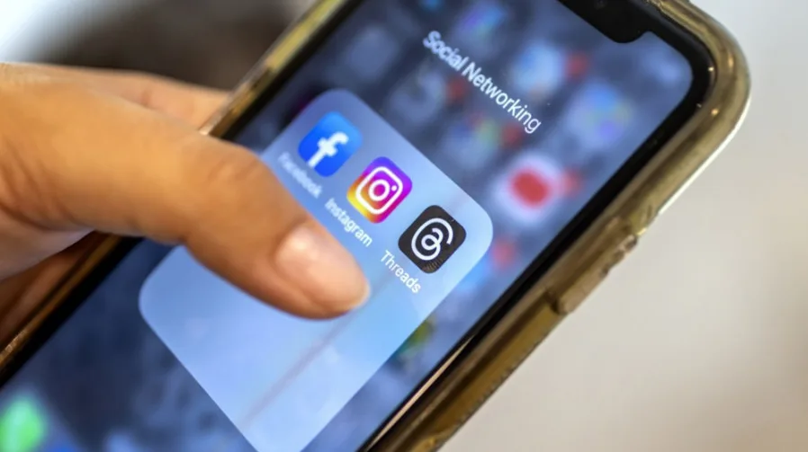 Krupni kadar ruke korisnika koja prstom dodiruje ikone Facebooka, Instagrama i Threadsa na ekranu pametnog telefona.
