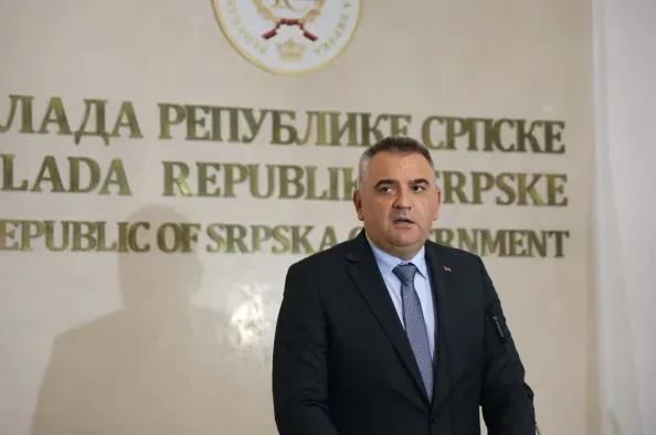 Čovjek u tamnom odijelu i plavoj kravati govori ispred natpisa na zidu na kojem piše "Vlada Republike Srpske".