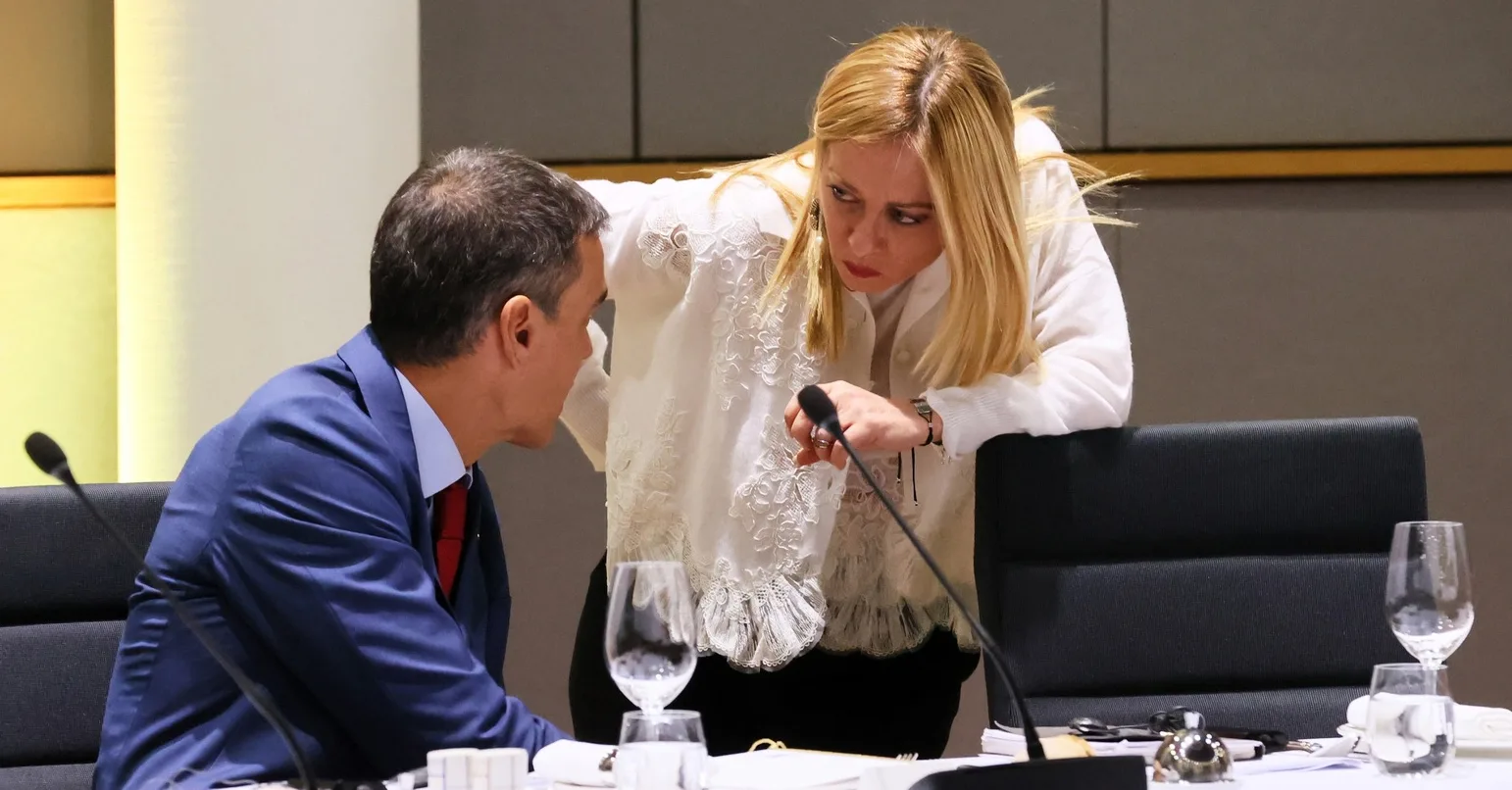 Muškarac u plavom odijelu i žena u bijeloj bluzi razgovaraju na sastanku.