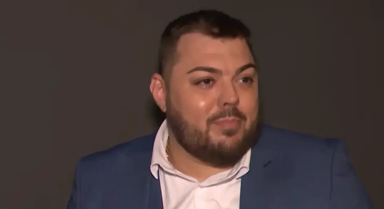 Portret mladog muškarca s bradom, obučenog u plavo odijelo i bijelu košulju.
