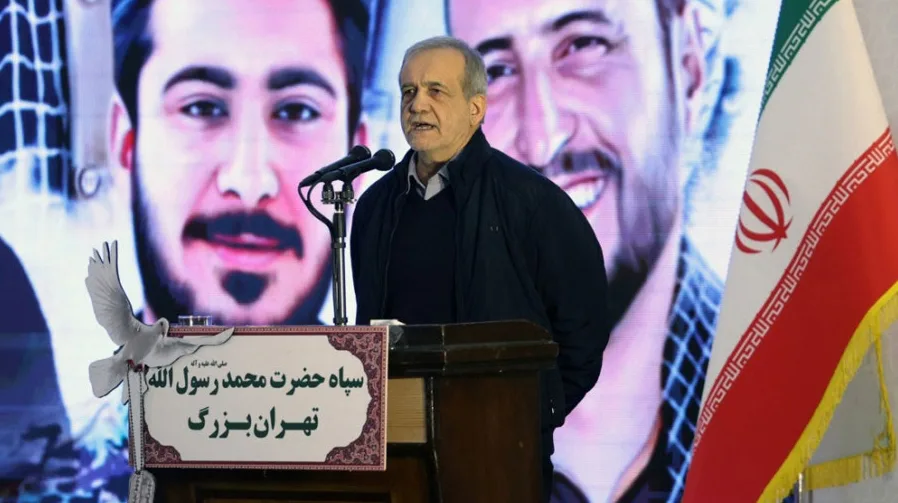 Muškarac srednjih godina, obučen u tamni prsluk preko tamne rolke, govori za govornicom ispred dva velika ekrana. Na lijevom ekranu vidi se lice mladog muškarca, a na desnom ekranu je iranska zastava. Pored njega se nalazi tabla sa natpisom na arapskom jeziku i bijela golubica koja simbolizira mir.