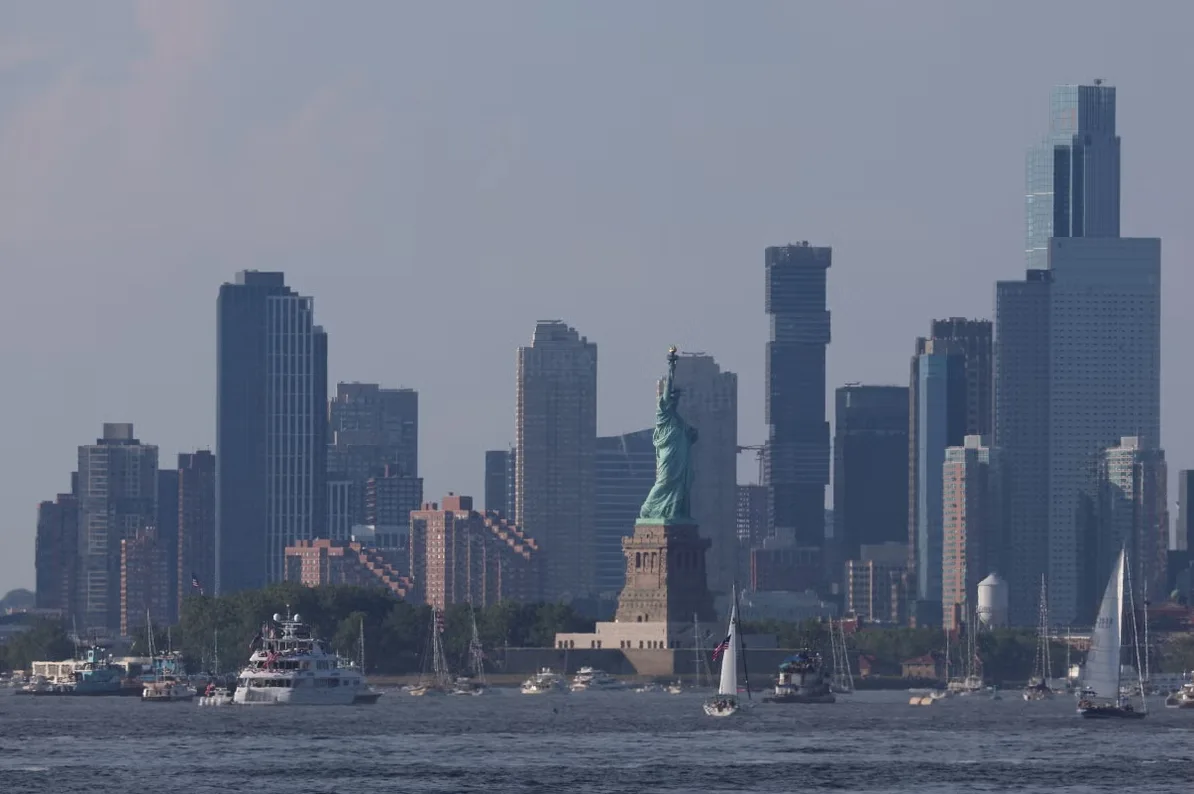 Kip slobode u pozadini sa modernim neboderima New Yorka i brodovima na vodi.