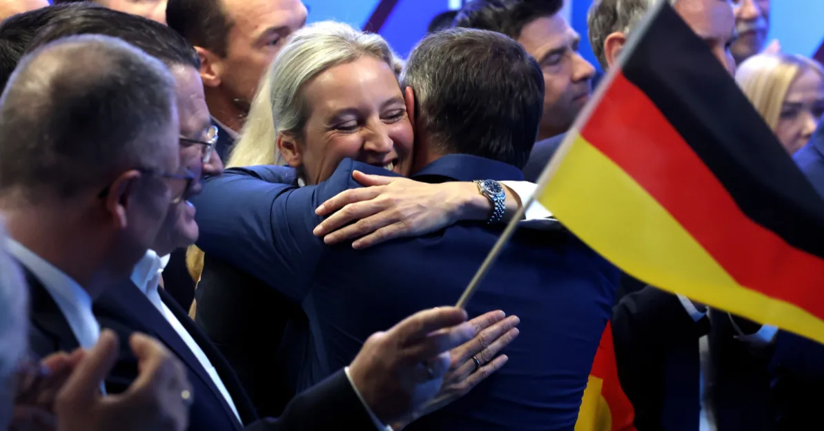 Žena i muškarac se grle, žena drži njemačku zastavu.